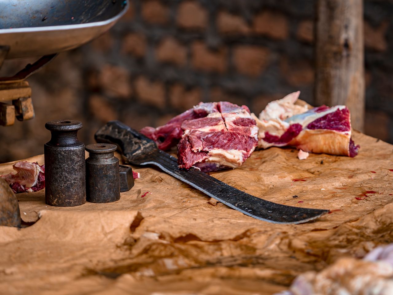 Close-up of raw meat and cleaver on a rustic table, showcasing traditional butchery tools.