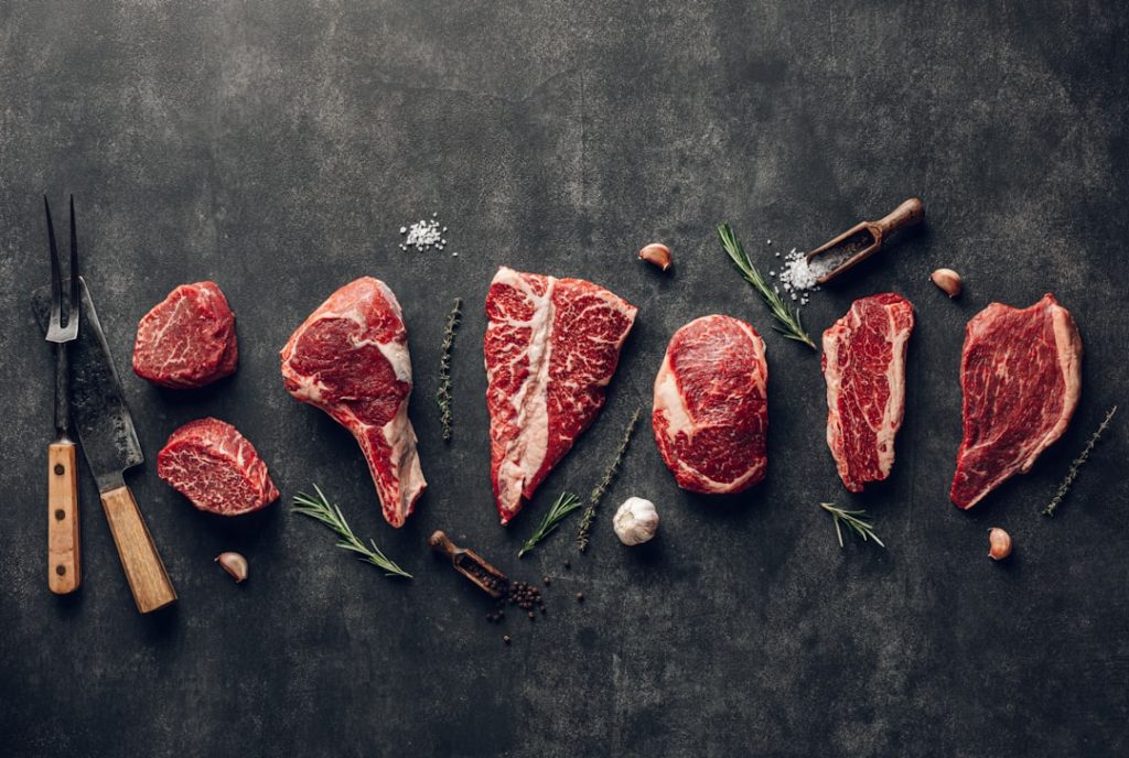 Various types of raw pork meat and beef on black board